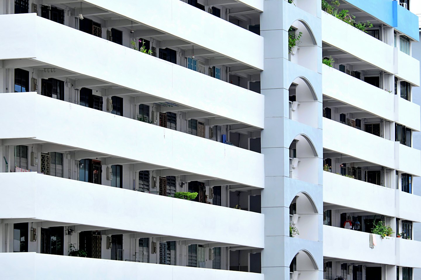 Moderní bytový dům s bílými balkony a obloukovými designovými prvky.